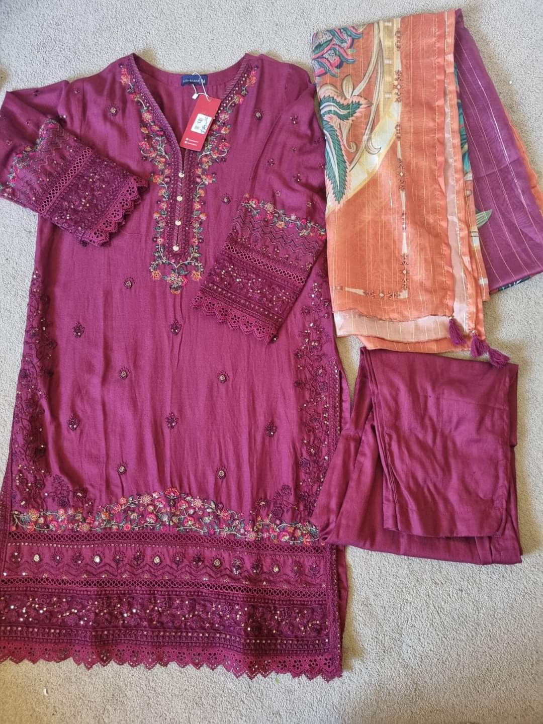 Purple embroidered outfit with matching pants and a pink dupatta on a neutral background